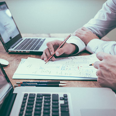 person holding pencil near laptop computer
